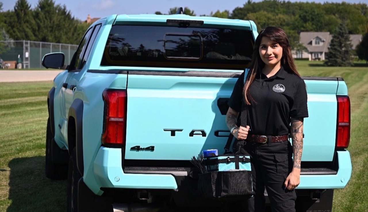 Heidi standing beside her turquoise work truck with organizing supplies